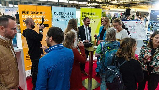 Viele Personen stehen an einem Messestand