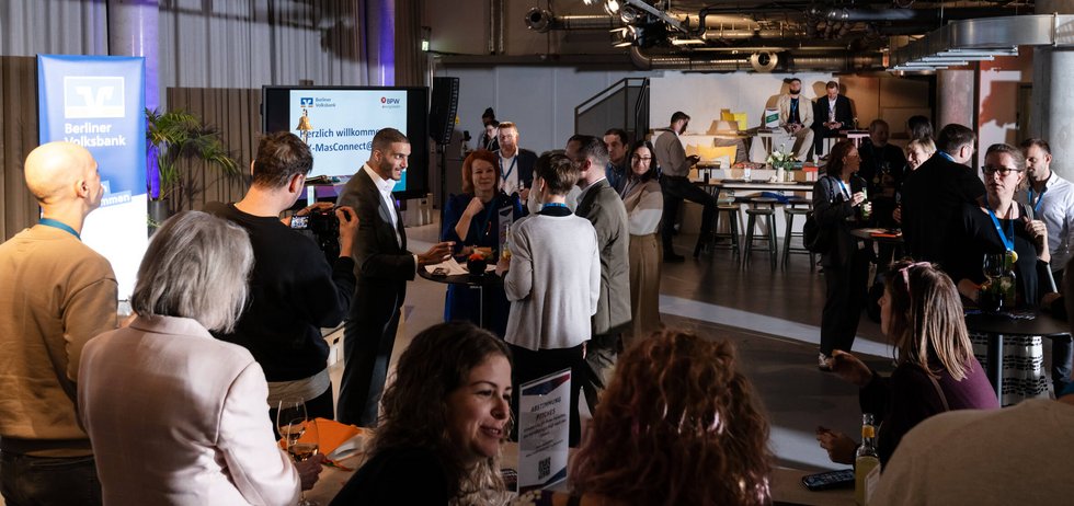 Zahlreiche Personen unterhalten sich in einem Veranstaltungssaal