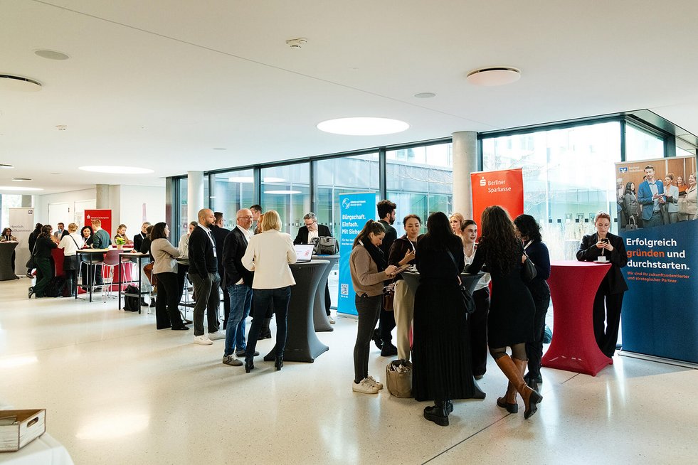 Networking-Szene beim Finanzforum mit Ausstellerständen und großen Fensterfronten.