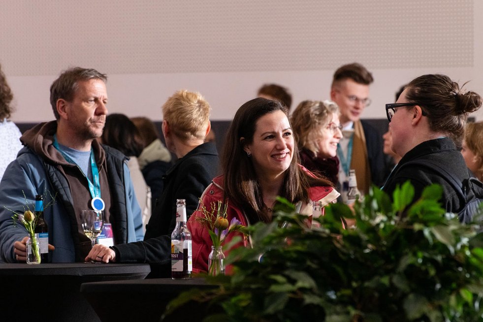 Gruppe von Menschen im Gespräch bei einem Networking-Event mit Getränken an Stehtischen