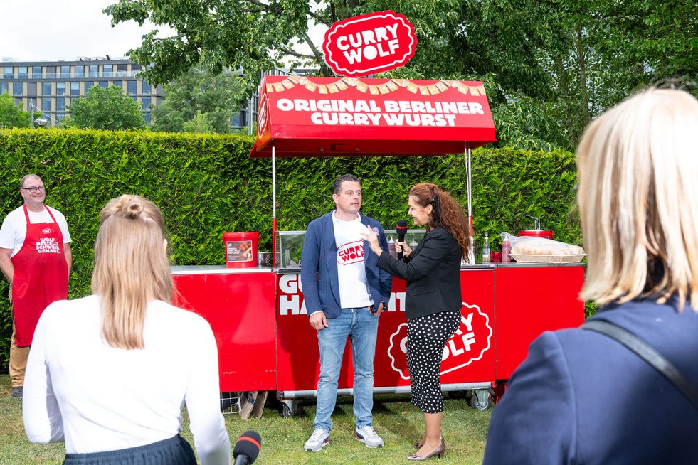 Interview mit einem Vertreter von Curry Wolf vor dem Currywurst-Stand bei einer Netzwerkveranstaltung des Businessplan-Wettbewerb Berlin-Brandenburg (BPW).
