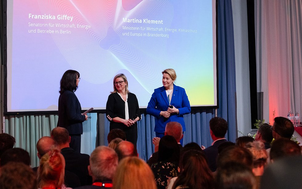 Drei Frauen auf einer Bühne im Gespräch vor Publikum.