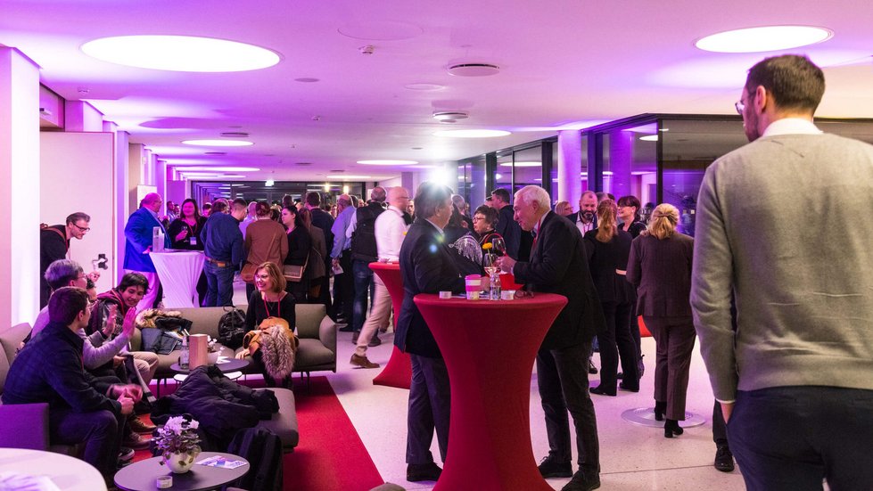 Netzwerken in einem Foyer. Zahlreiche Gäste unterhalten sich.
