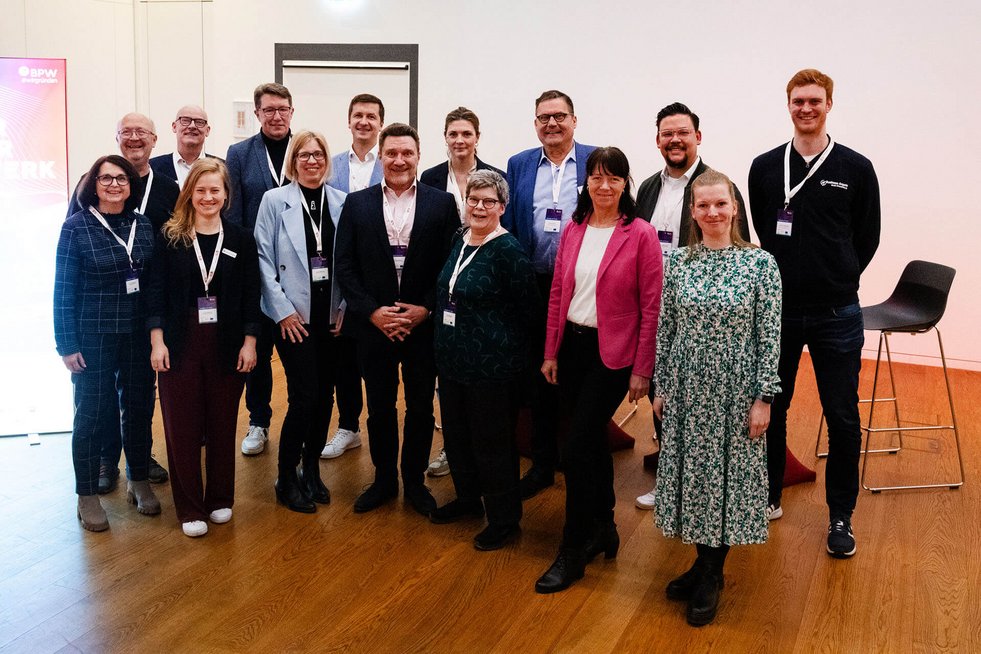 Gruppenbild - Menschen stehen aufgereiht und blicken in die Kamera