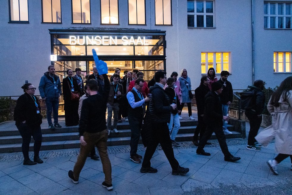 Menschen verlassen ein Gebäude mit dem Schriftzug „Bunsen Saal“ und gehen nach draußen.