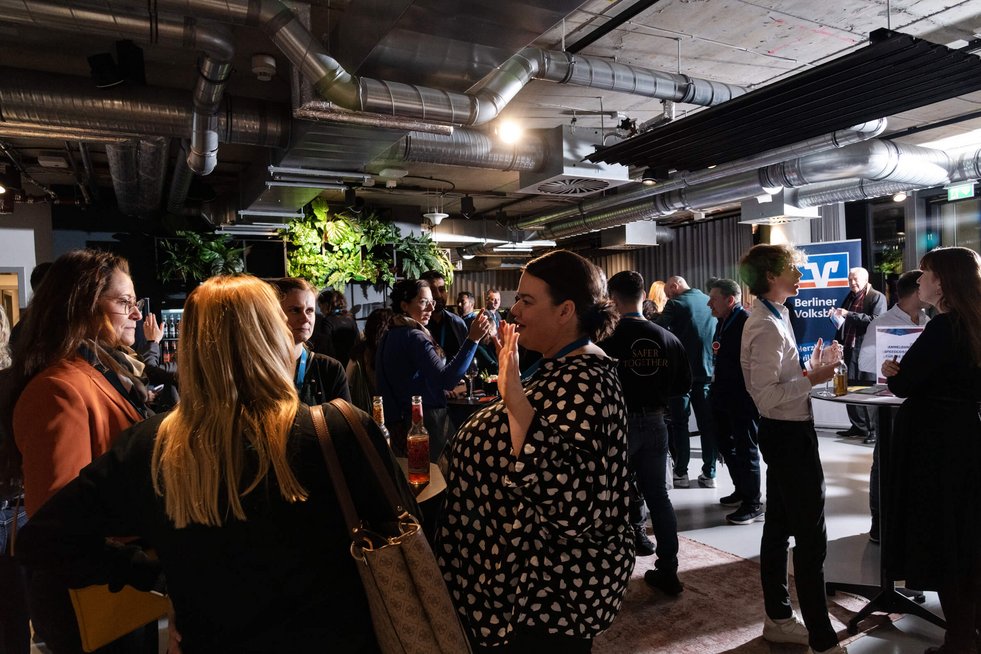 Zahlreiche Personen befinden sich in einem stimmungsvollen Veranstaltungssaal