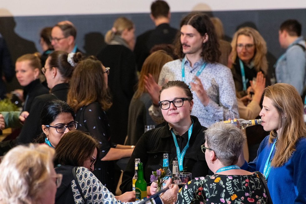 Mehrere Personen stehen zusammen und unterhalten sich bei einem Event mit Getränken.