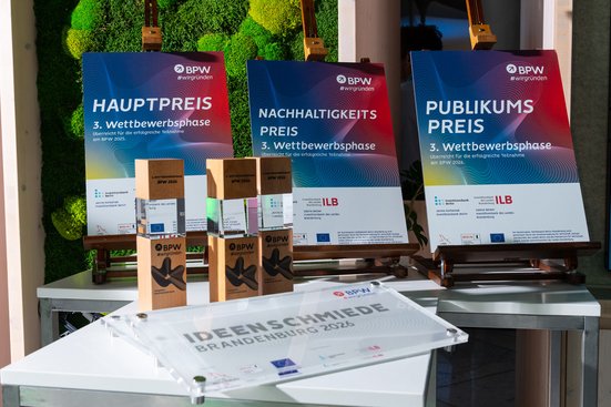 Urkunden, Trophäen und Auszeichnungen der dritten Wettbewerbsphase des Businessplan-Wettbewerb Berlin-Brandenburg (BPW) sind auf einem Präsentationstisch ausgestellt. Zu sehen sind Hauptpreis, Nachhaltigkeitspreis, Publikumspreis und die Auszeichnung „Ideenschmiede Brandenburg 2026“.
