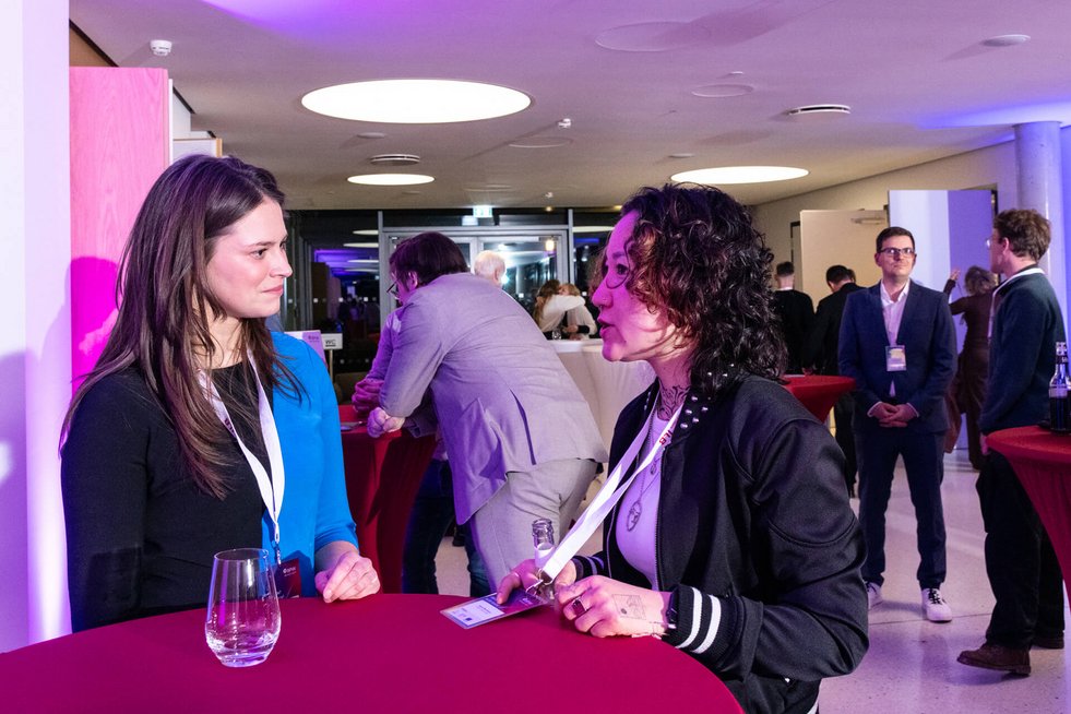 Zwei Frauen stehen an einem Stehtisch und unterhalten sich