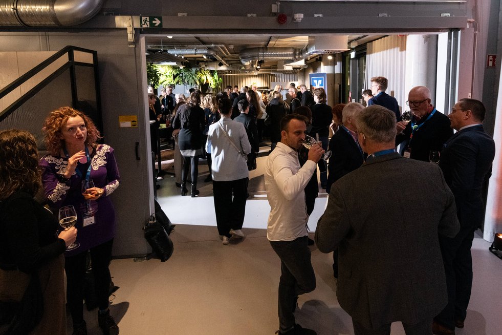 Blick ins Foyer eines Veranstaltungssaals mit Menschen, die zu einer Veranstaltung kommen und ein Begrüßungsgetränk erhalten