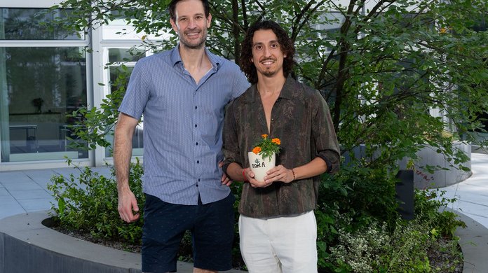 Das Gründungsduo von Plant A steht zusammen und ein Gründer hält das Produkt, die pflanzbare Zahnbürste in der Hand