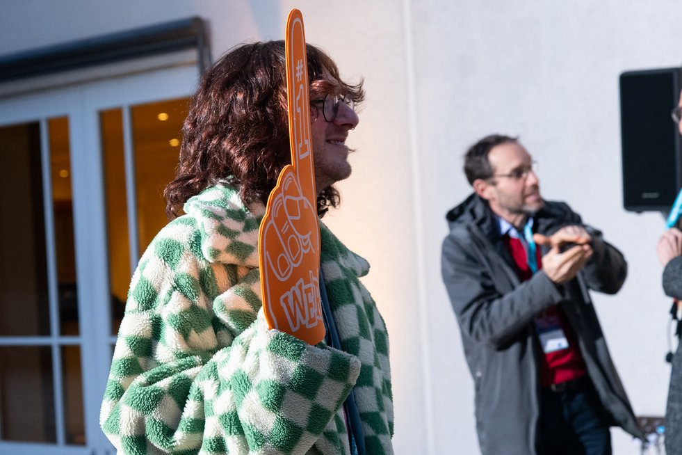 Zwei Personen sind auf dem Bild, eine Person hält ein Schild hoch