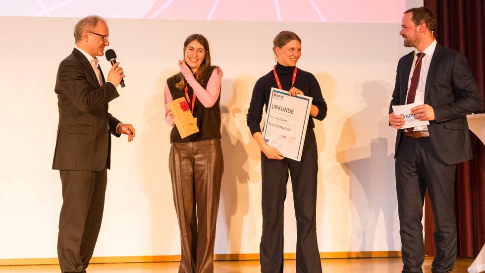 Verleihung eines Preises auf der Bühne. Zwei Siegerinnen sprechen mit zwei Laudatoren