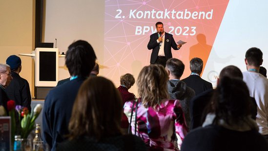 Gastgeber hält Begrüßung auf einer Bühne
