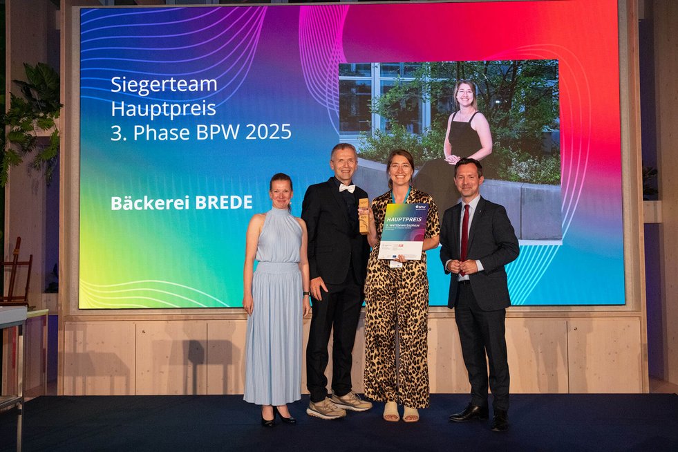 Gründerin mit Pokal in der Hand, neben ihr die Moderatorin und die Laudatoren