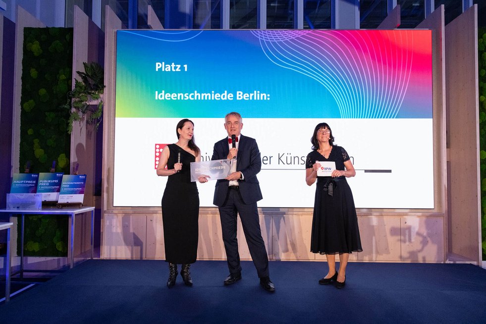 Auszeichnung der UdK durch Kai-Uwe Bindseil von Berlin Partner, daneben steht die Moderatorin