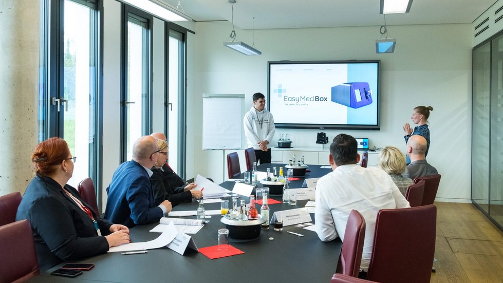 Teilnehmer präsentiert seine Geschäftsidee vor einer sechs Jurymitgliedern