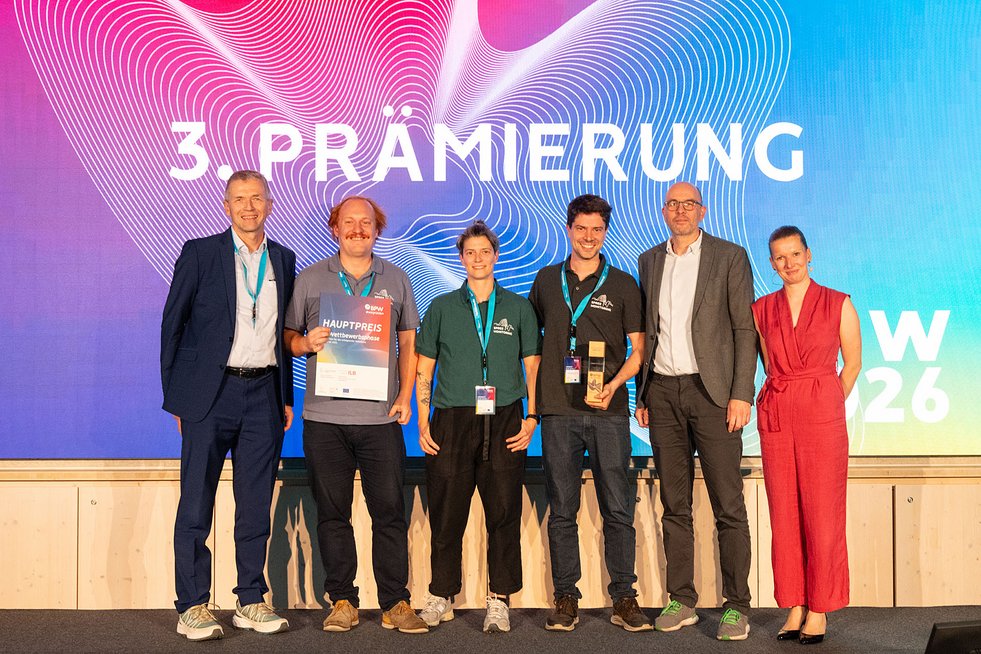 Gewinnerteam und Gratulierende bei der dritten BPW-Prämierung auf der Bühne mit Urkunde und Trophäe.