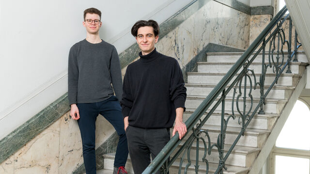 Zwei Männer stehen für ein Foto auf einer Treppe und blicken Richtung Kamera